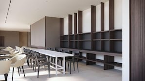 A modern conference room with a long table and chairs, a large whiteboard, and built-in shelving units. - B21 Hotel (Bari)