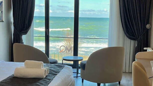Habitació d'hotel amb un llit gran, dues butaques, una taula petita i vista a l'oceà.