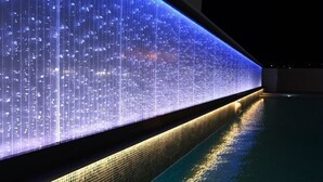 Una piscina amb una paret d'aigua que projecta patrons de llum verticals.