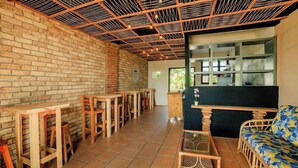 Un cafè acollidor amb parets de maó, taules de fusta i un mostrador negre.