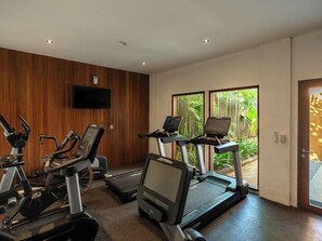 Une salle de sport équipée de vélos d’appartement, de machines elliptiques et de tapis de course.