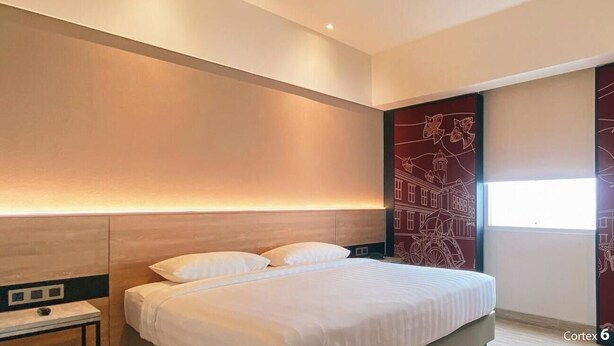 Une chambre d’hôtel moderne avec un grand lit, une table de chevet et un mur orné d’une fresque représentant un paysage urbain.