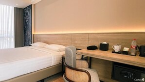 Une chambre d’hôtel équipée d’un lit, d’un bureau, d’une chaise, d’une machine à café et d’un mini-bar.