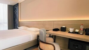 Une chambre d’hôtel équipée d’un lit, d’un bureau, d’une chaise et d’un mini-bar.