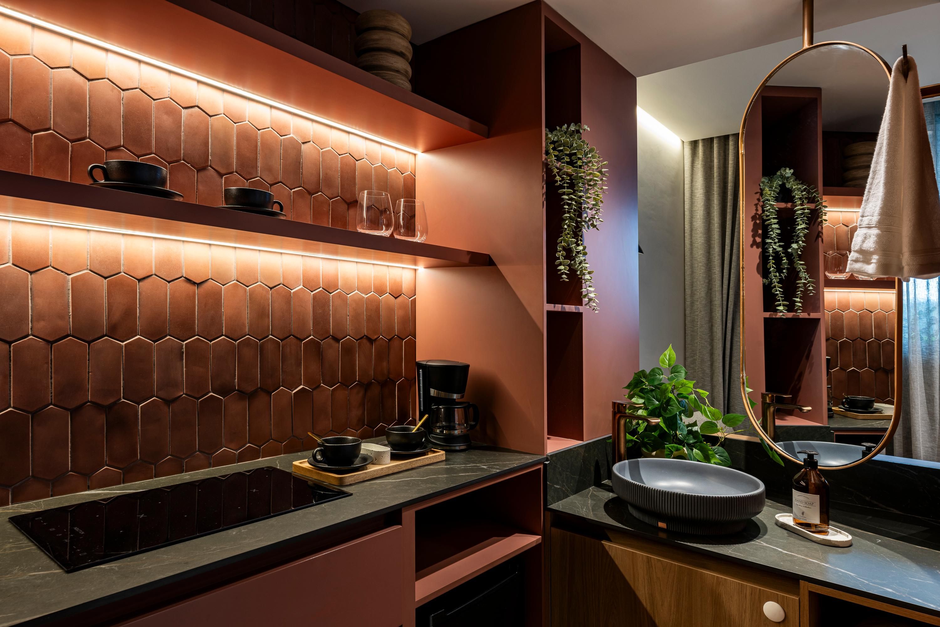 Un baño moderno con un revestimiento de azulejos hexagonales, una cafetera, un lavabo con plato redondo y un espejo grande.