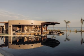 A modern building with a pool, surrounded by palm trees and a clear sky. - Unda (Corfu)