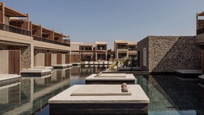 Ein modernes Resort mit einem zentralen Pool, mehreren Gästezimmern und einer Steinmauer.