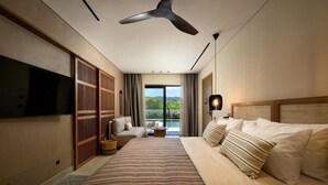Ein modernes Hotelzimmer mit einem großen Bett, einem Flachbildfernseher, einem Deckenventilator und Blick ins Freie.