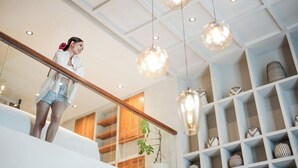 A modern interior with a staircase, pendant lighting, and a shelving unit with decorative items. - Secana Beachtown (Canggu)