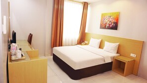 Una camera d'albergo con un letto, un comodino e una scrivania con sedia.