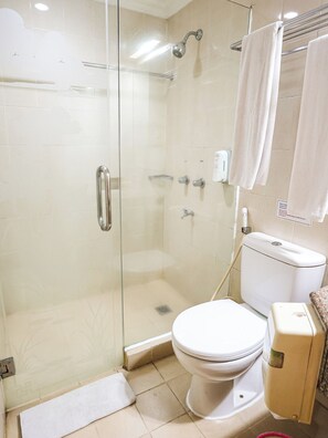Une salle de bain avec une douche à parois de verre, des toilettes et un lavabo équipé d’un distributeur de savon.