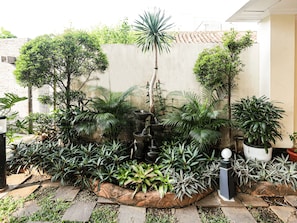 A garden with a variety of plants and a small fountain. - Hotel Grande Lampung Powered by Archipelago (Bandar Lampung)
