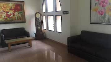 A room with a sofa, a bench, a clock, a painting, and a sign indicating a smoking area.