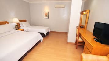 A hotel room with two beds, a desk with a television, a chair, a lamp, and a picture on the wall.
