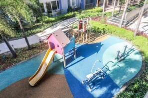A playground with a slide, climbing structures, and exercise equipment. - PRS at One Palm Tree Villa Near Airport (Pasay)