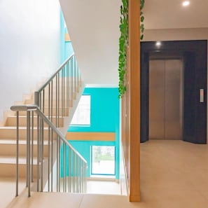 A staircase with metal railings leading to a landing with a large window. - Sans Hotel Alexander Bandung (Bandung)