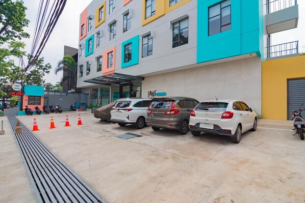 A multi-story building with colorful facades, parked cars, and a visible entrance. - Sans Hotel Alexander Bandung (Bandung)