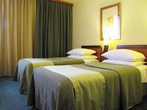 A hotel room with two beds, a headboard, a framed picture on the wall, and a curtain. - Perla Casino And Hotel (Nova Gorica)