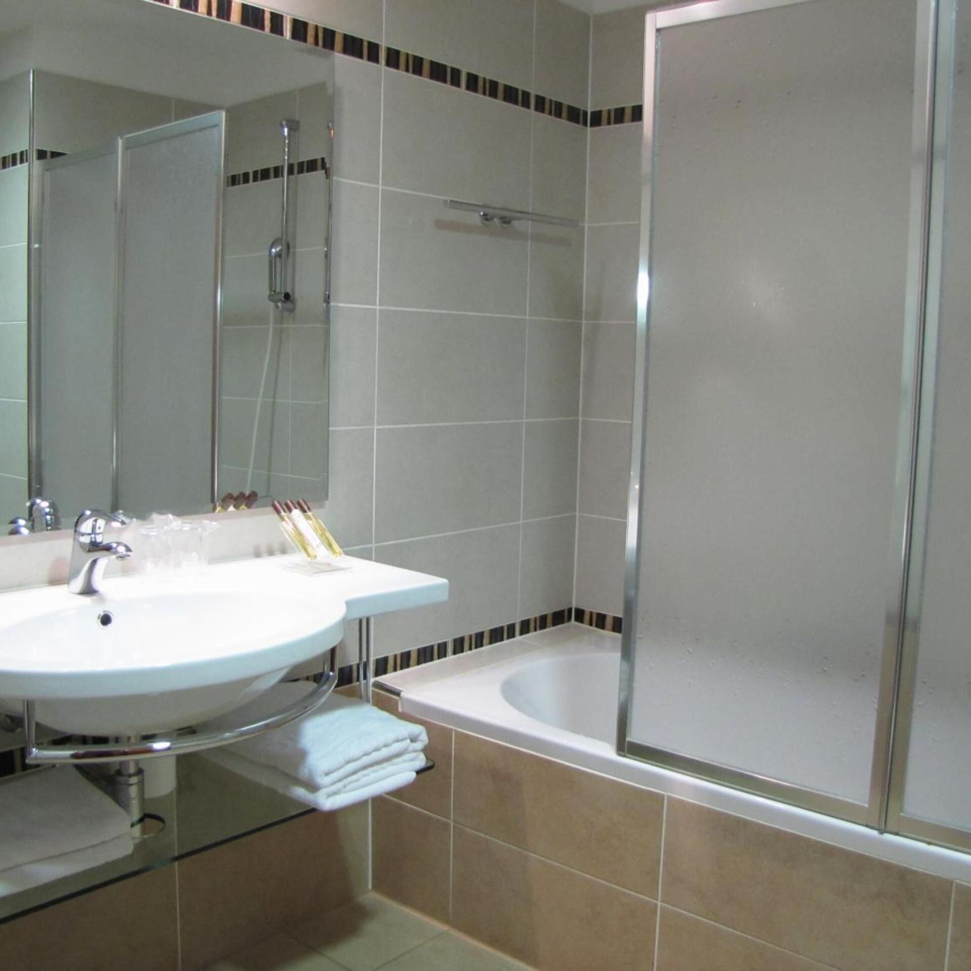 A bathroom with a white sink, a mirror, a shower enclosure, and a bathtub.