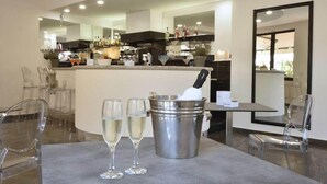 Una cocina moderna con barra, una mesa de comedor con dos vasos de vino blanco y un cubo de metal con una botella.