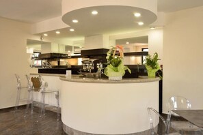 Une cuisine moderne avec un îlot central, des chaises transparentes et des plantes en pot.