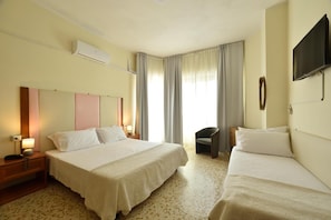 Quarto de hotel com duas camas, uma televisão de tela plana, ar condicionado e uma cadeira.
