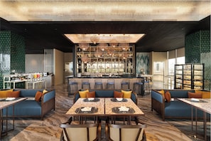 A modern restaurant with a bar area, seating arrangements, and a view of the cityscape. - Oakwood Hotel and Apartments Grand Batam (Batam)