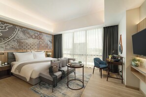 Habitació d'hotel moderna amb un llit, zona de seients, escriptori i televisió.