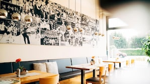 Un restaurante con una larga mesa compartida, cabinas y una pared decorada con fotografías en blanco y negro.