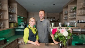 A bar area with wooden shelves, a cash register, and a vase with flowers.
