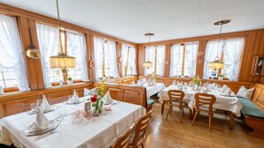 A dining area with wooden paneled walls, white tablecloths, and wooden chairs.