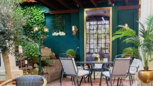 Eine Terrasse im Freien mit Tisch und Stühlen, einem kleinen Wasserfall und verschiedenen Pflanzen.