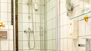 Ein Badezimmer mit einer Duschkabine, einem weißen Waschbecken und einer Toilette.