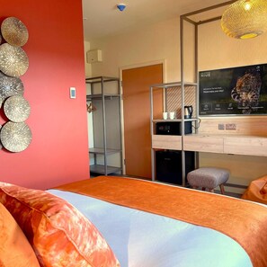 A hotel room with a bed, a desk with a computer, a coffee machine, and a TV displaying a leopard. - Hex Wildlife Hotel At Yorkshire Wildlife Park (Doncaster)