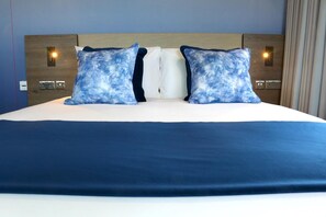 A hotel room with a large bed, two pillows, a wooden headboard, and wall-mounted light fixtures. - Hex Wildlife Hotel At Yorkshire Wildlife Park (Doncaster)