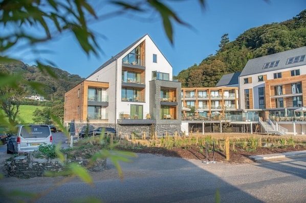 A modern building with a sloped roof, large windows, and a mix of wood and stone materials. - Harbour Beach Club, Hotel & Spa (Salcombe)