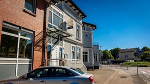 A two-story building with a restaurant sign, a fire escape, and a car parked in front. - Hotel & Gastro Adler Gmbh (Itzehoe)