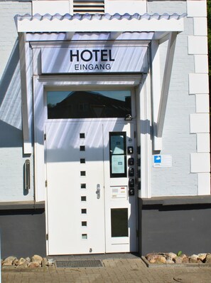 Entrada de hotel con un letrero que dice "HOTEL EINGANG" y un teclado para acceso a las habitaciones.