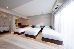 Une chambre d’hôtel moderne avec trois lits, une grande fenêtre avec des rideaux, un élément de séparation décoratif et un appareil de climatisation.