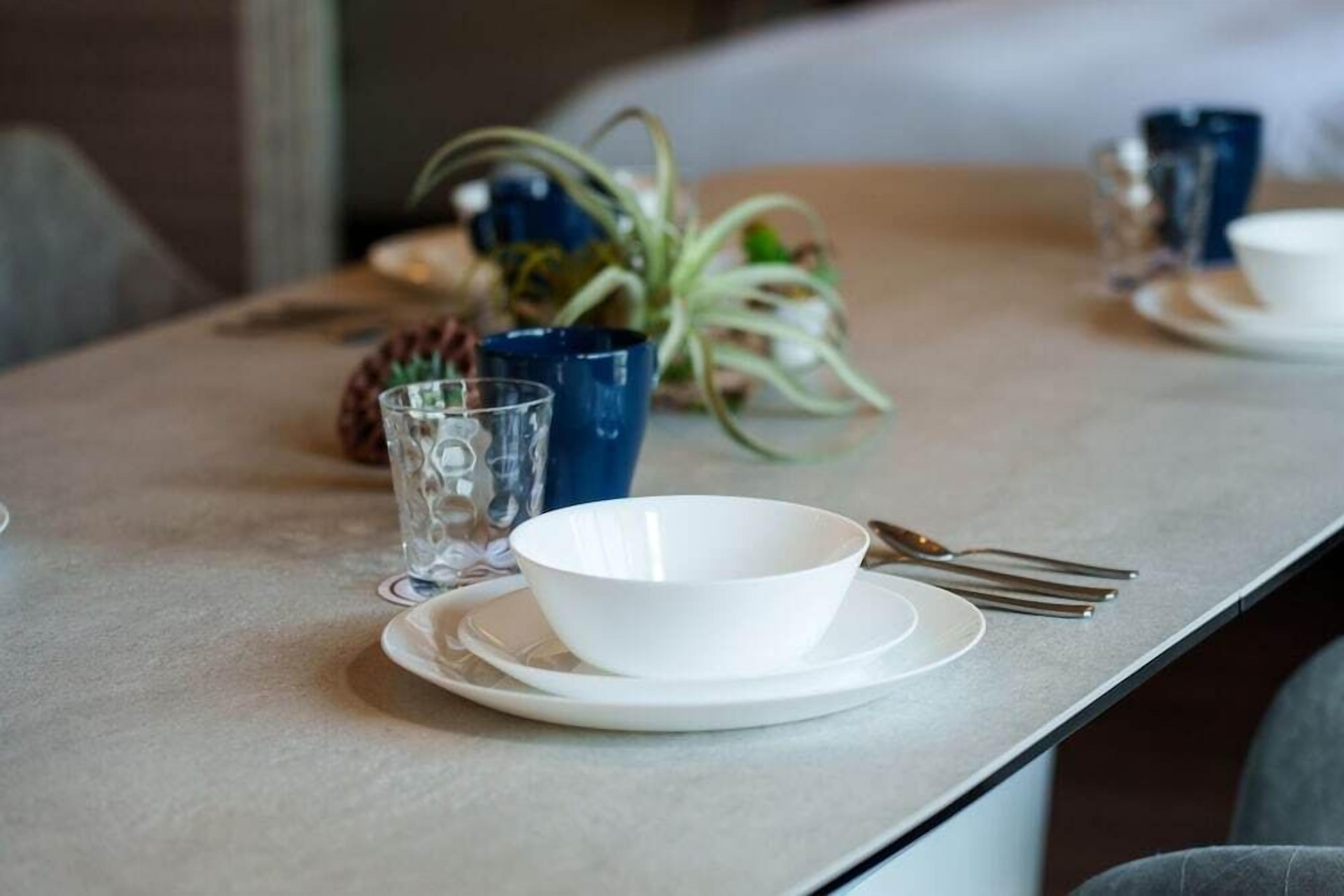 Una mesa dispuesta con un tazón blanco, un vaso y un tenedor.