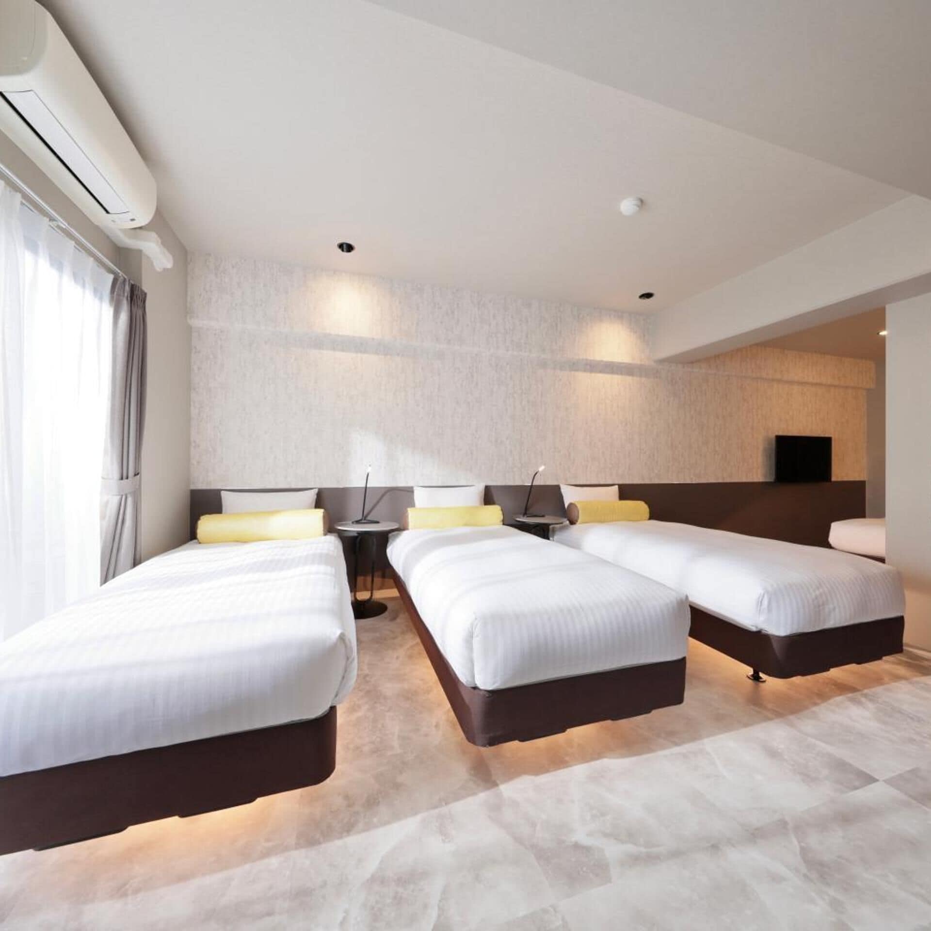 A hotel room with two beds, a small table, and a TV.