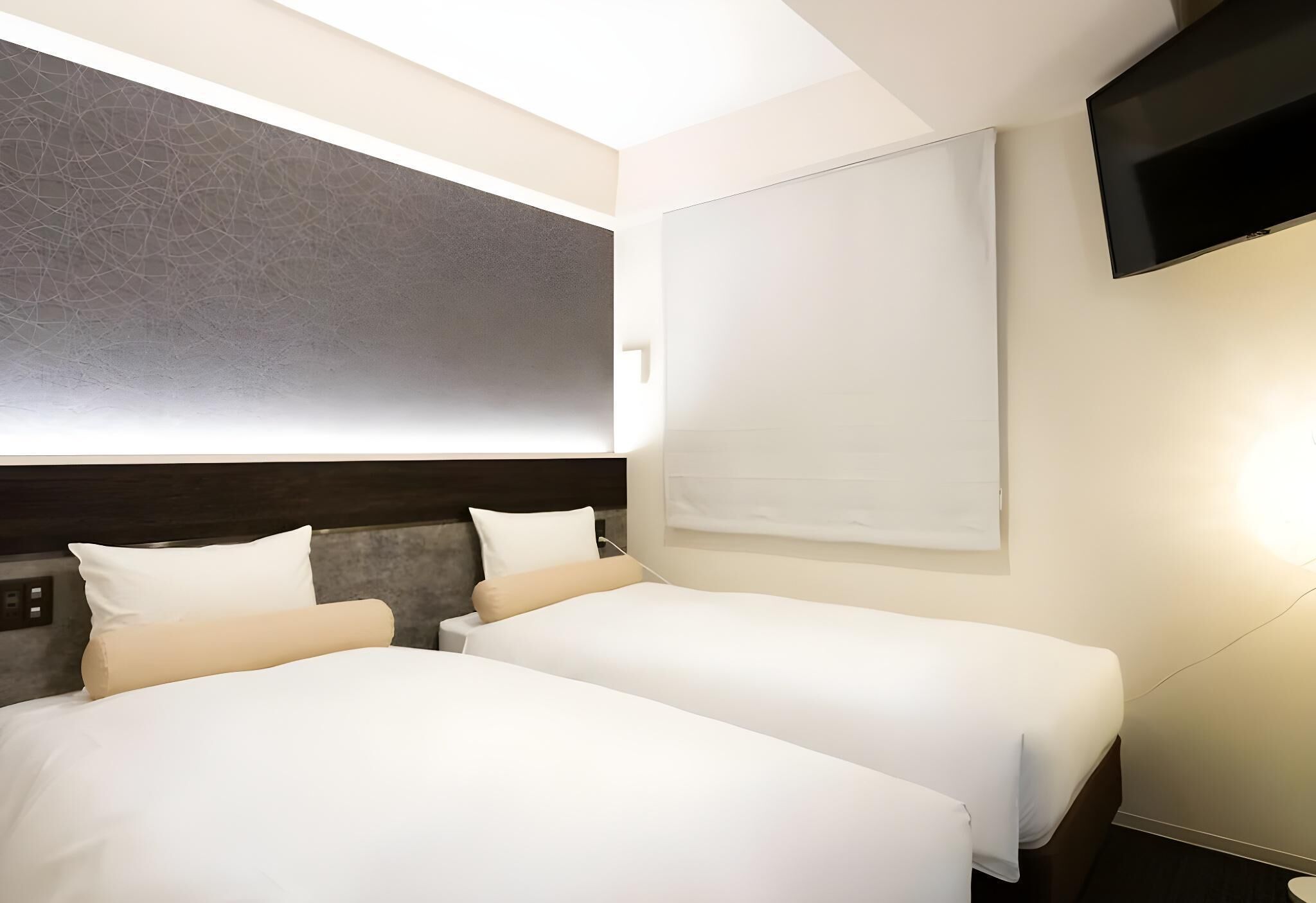 A hotel room with two beds, a flat-screen TV, and a large window.
