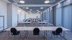 Une salle de conférence dotée de plusieurs tables et chaises, ainsi que de bouteilles d’eau et de verres.