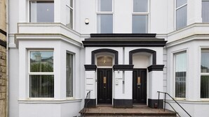 A white building with black-framed windows and a central black door with the number 7.