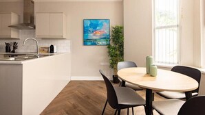 A modern kitchen with white cabinets, a stainless steel sink, and a round dining table with chairs.