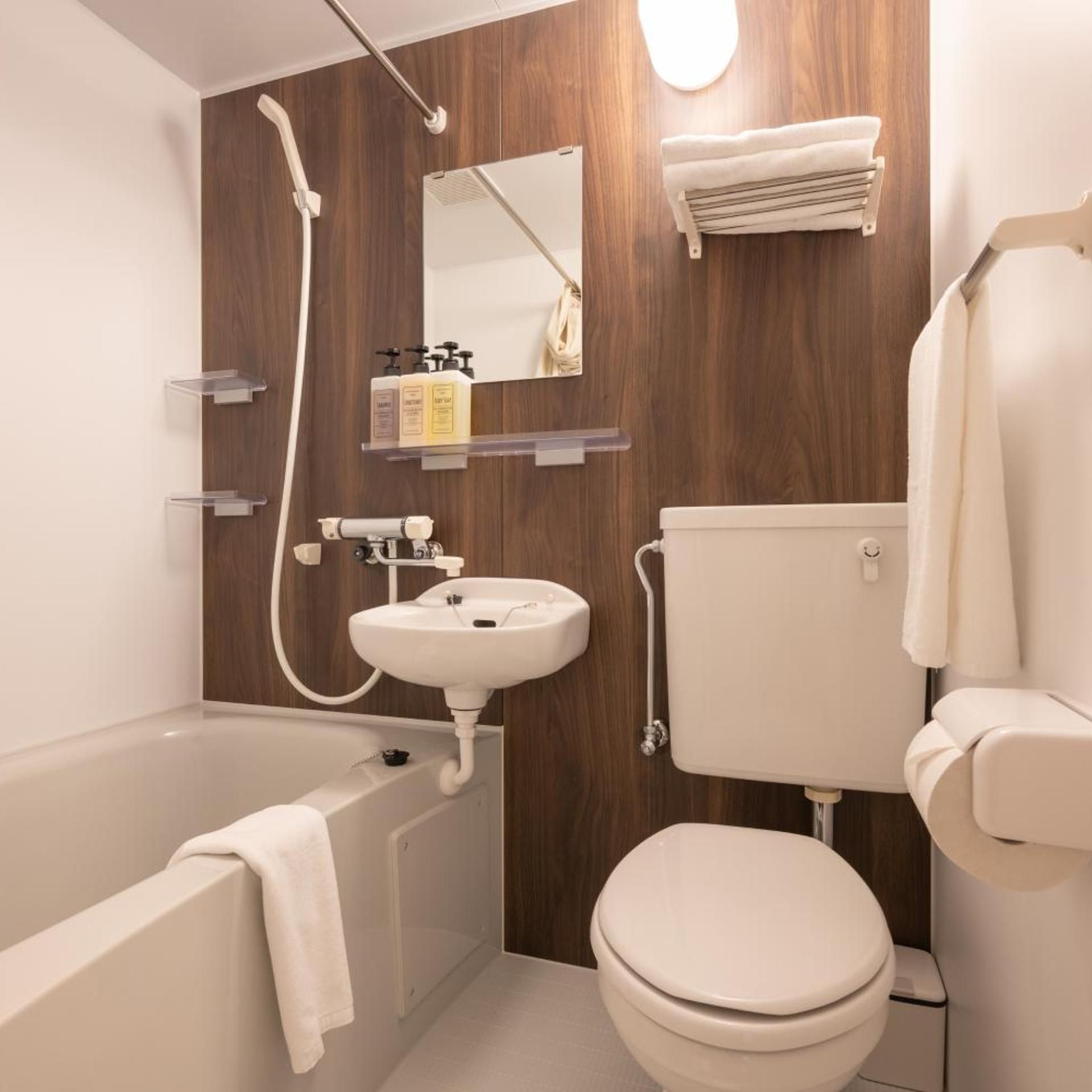 A modern bathroom with a bathtub, sink, toilet, and wooden wall paneling.