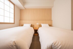 A hotel room with two single beds, a wooden headboard, a small bedside table, and a window with a grid pattern. - Fuji Hotel Kyoto Gojo (Kyoto)