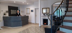 A reception area with a counter, a fireplace, and a staircase. - Hotel am Park (Braunschweig)
