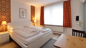 A hotel room with a double bed, two bedside lamps, a framed picture on the wall, and a window with curtains. - Hotel Am Park (Braunschweig)