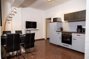 Une cuisine moderne avec un coin repas, équipée d’une télévision, d’un four à micro-ondes et d’une machine à café.